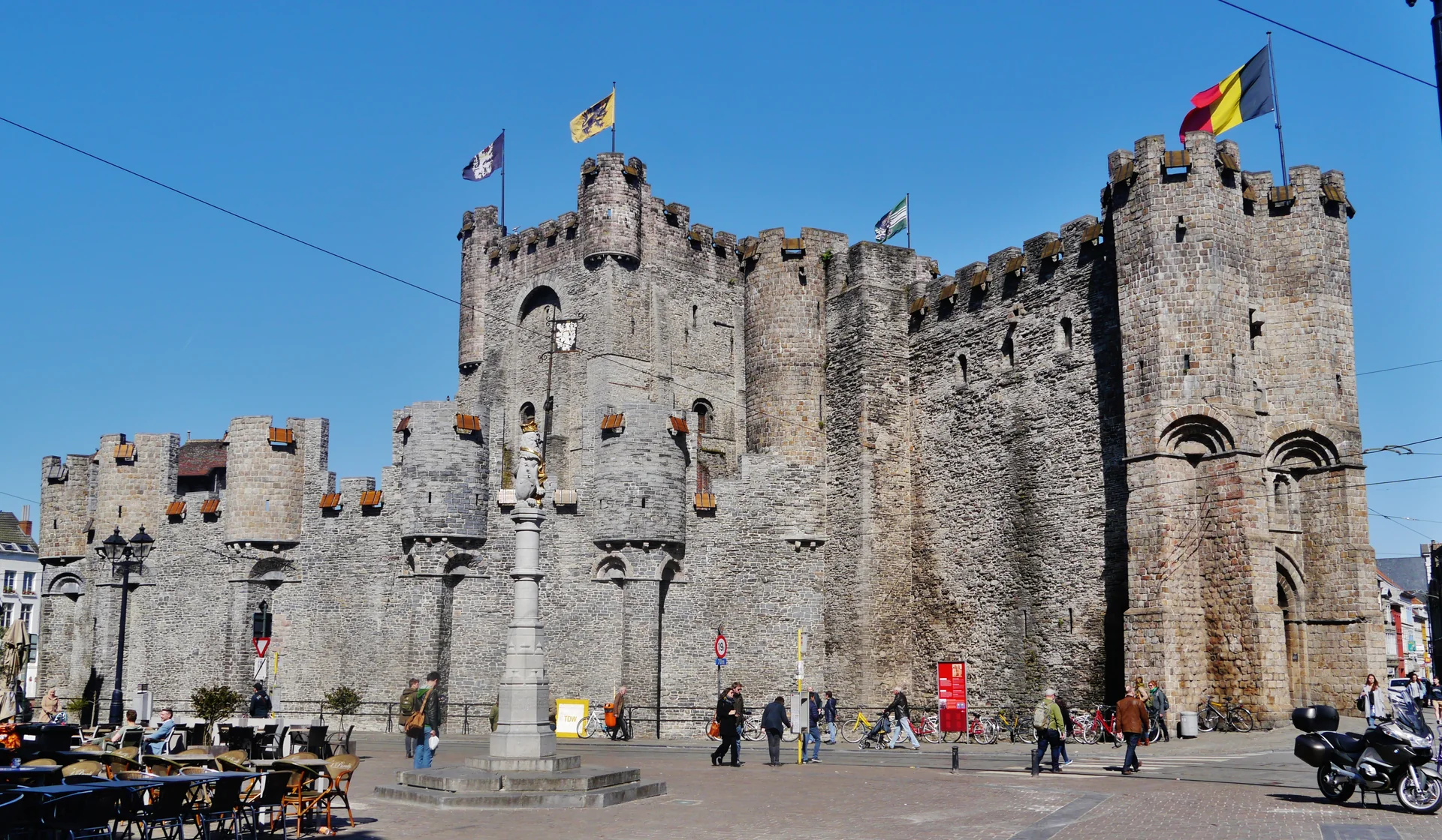 Fachada e torres do Castelo Gravensteen vistas da área urbana junto ao Sint-Veerleplein, em Gante.