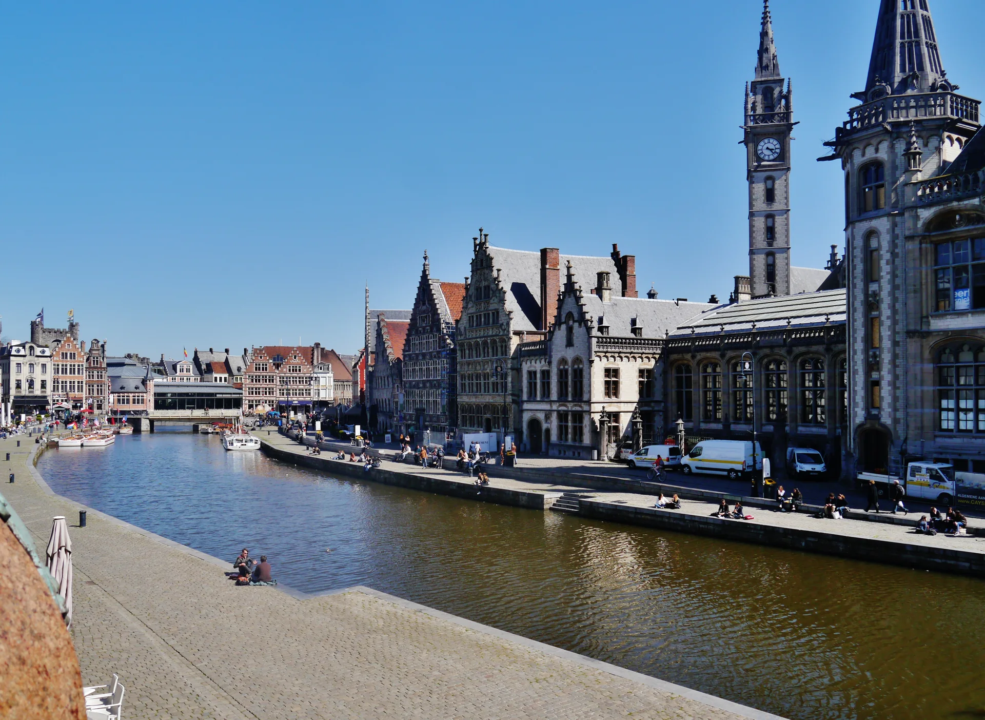 Cais de Graslei em Gante, com casas históricas junto ao canal sob céu azul.