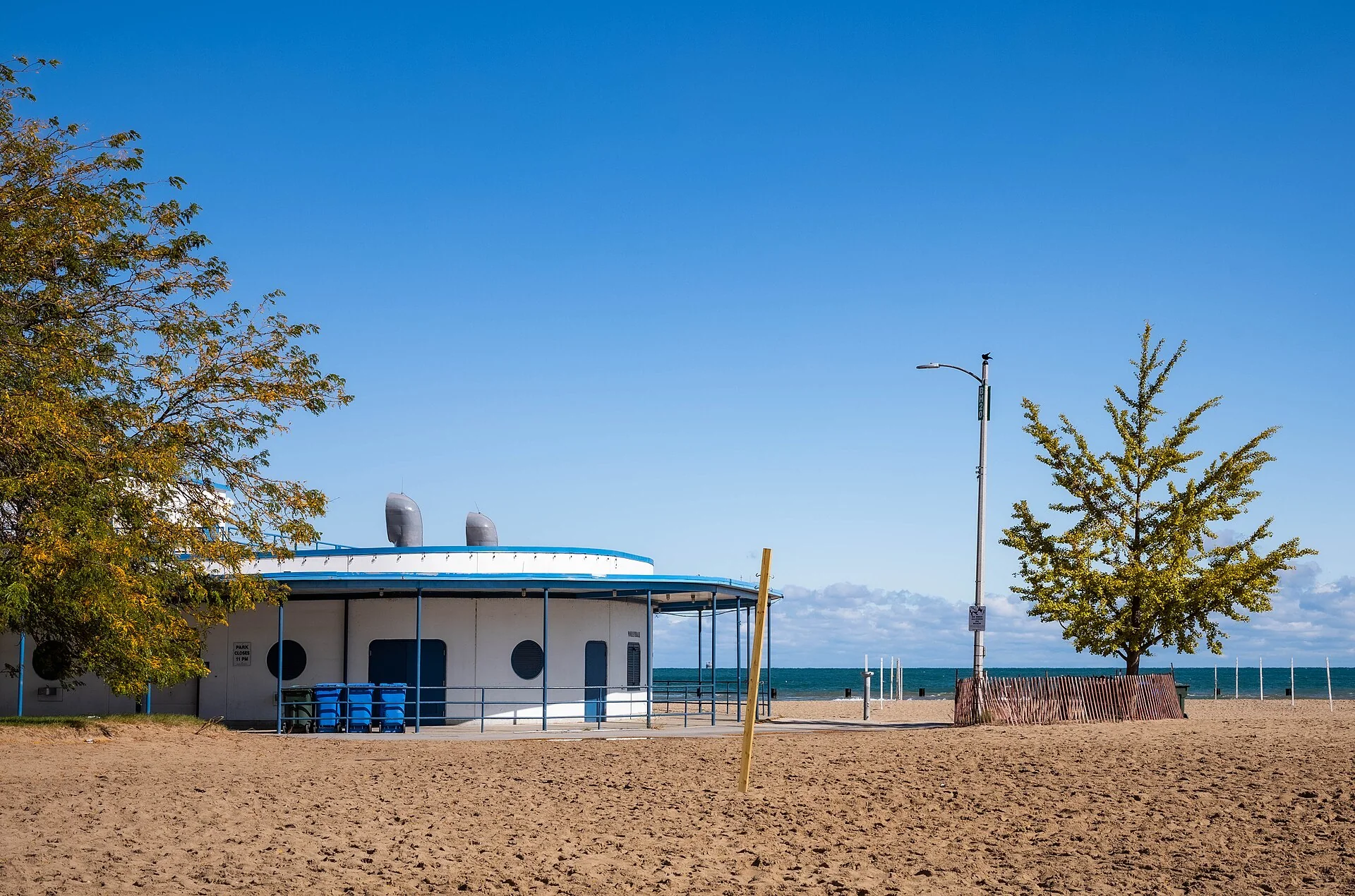Areia, edifício baixo de apoio e Lago Michigan em North Avenue Beach, em Chicago, sob céu azul.