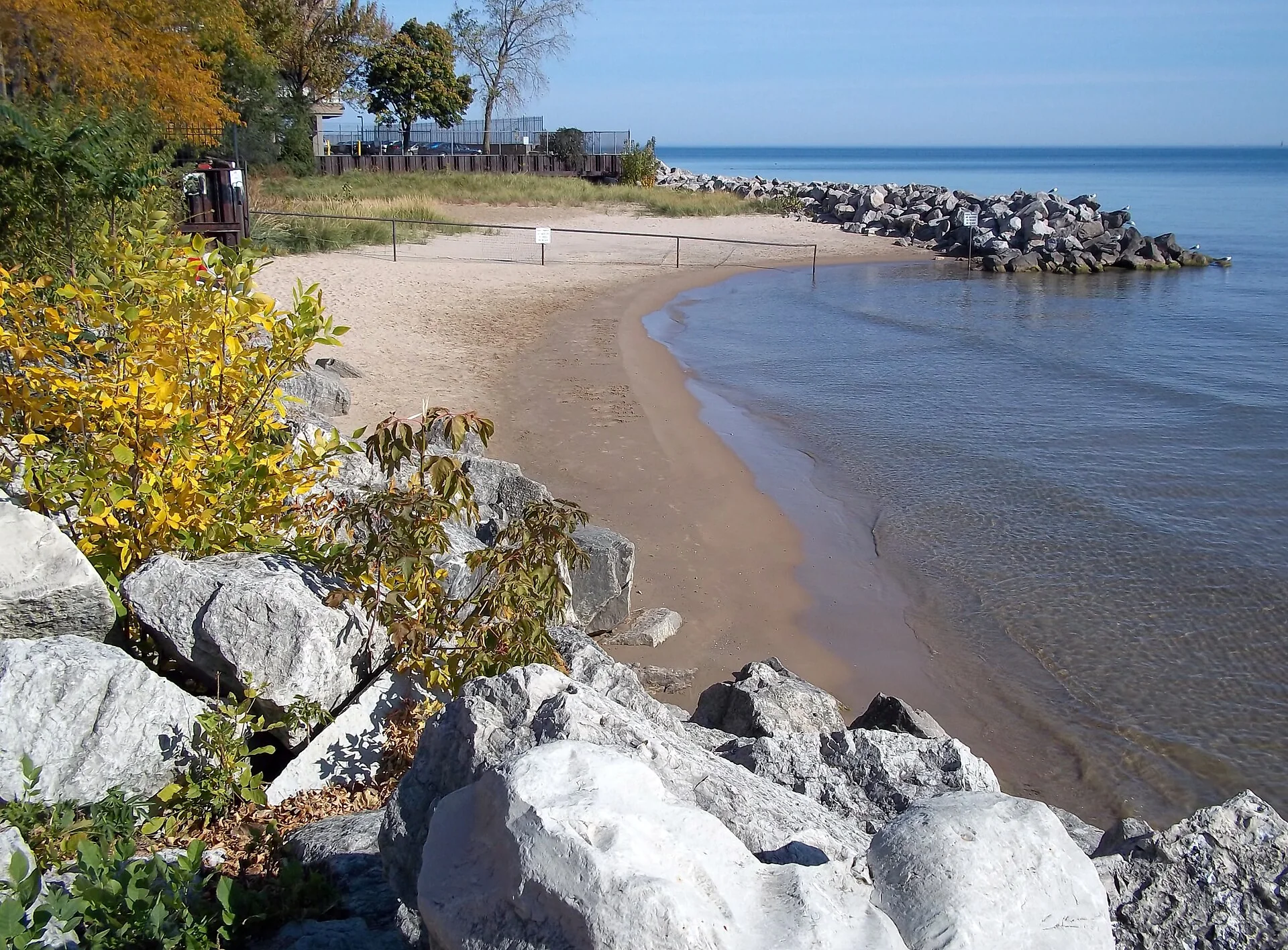 Pequena faixa de areia, pedras do quebra-mar, vegetação e Lago Michigan em Berger Park Beach, em Edgewater.