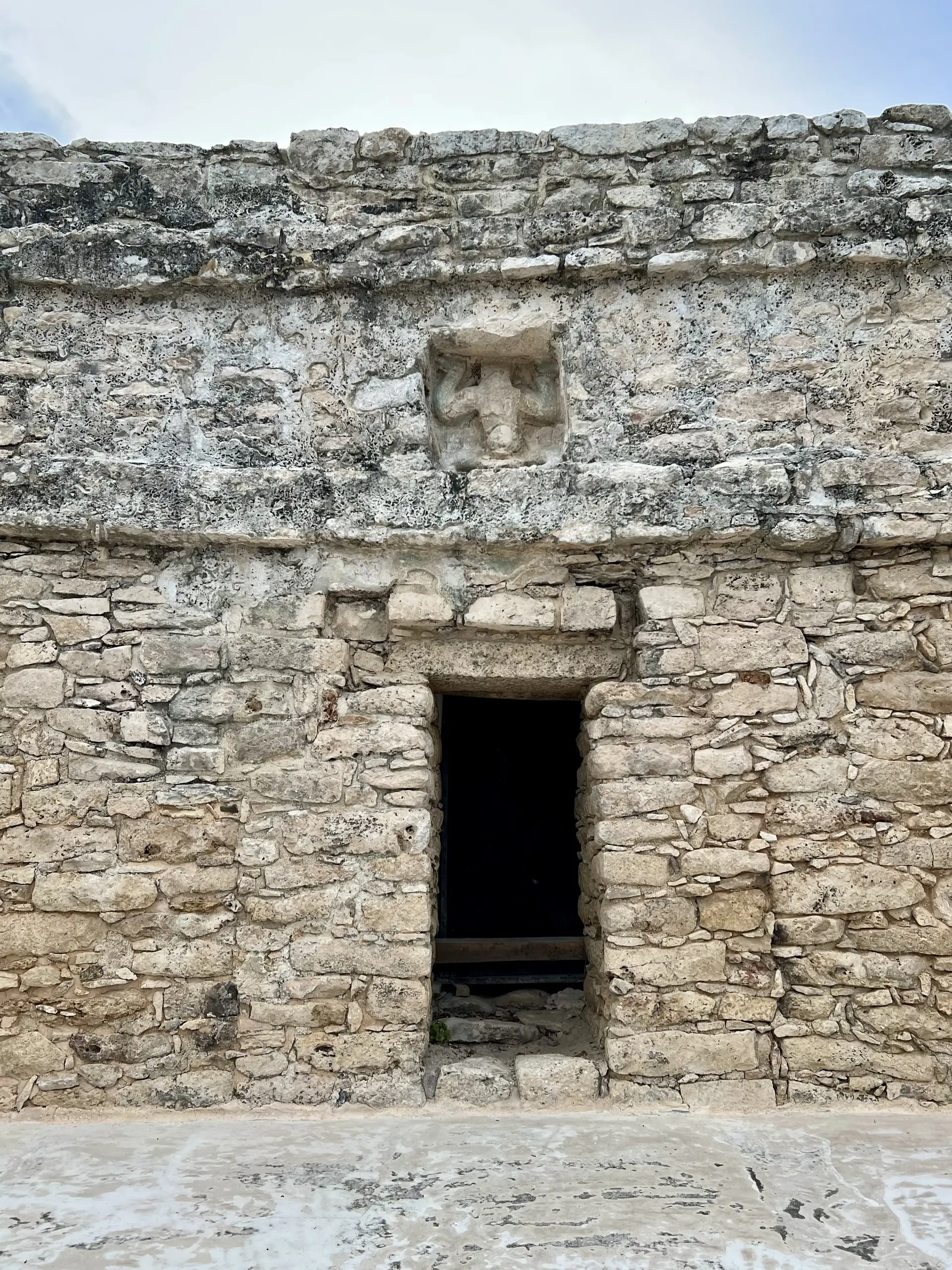 Detalhe da fachada de pedra no topo da pirâmide Nohoch Mul, em Cobá, com a figura do deus descendente sobre uma porta.