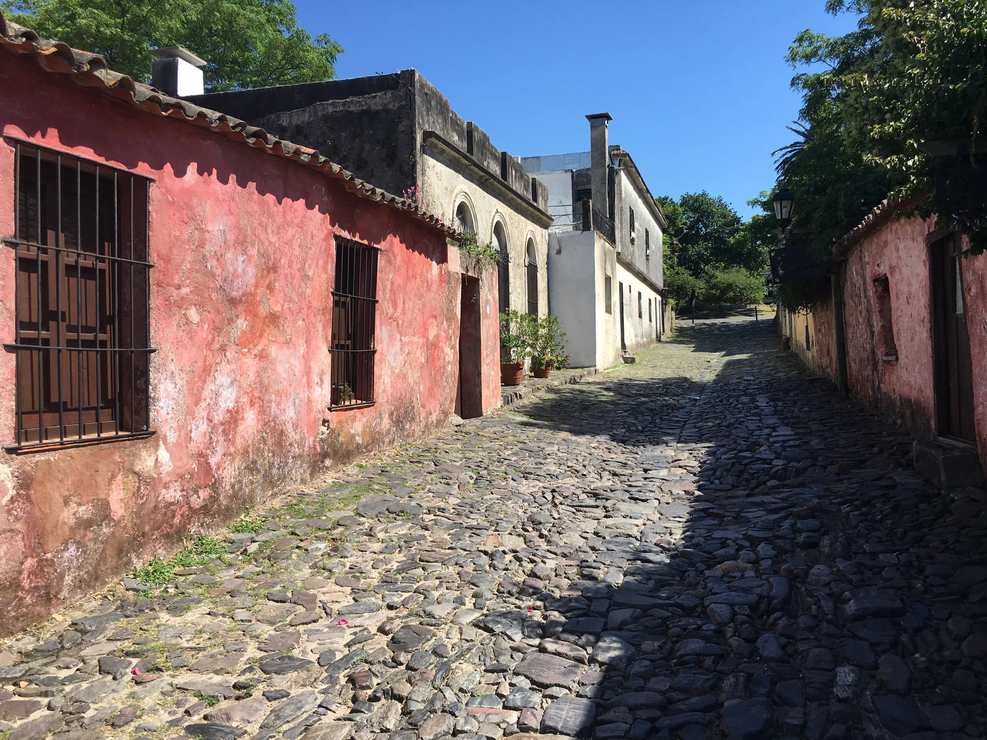 Trecho de pedras e fachadas históricas da Calle de los Suspiros, em Colônia do Sacramento, sob céu claro.