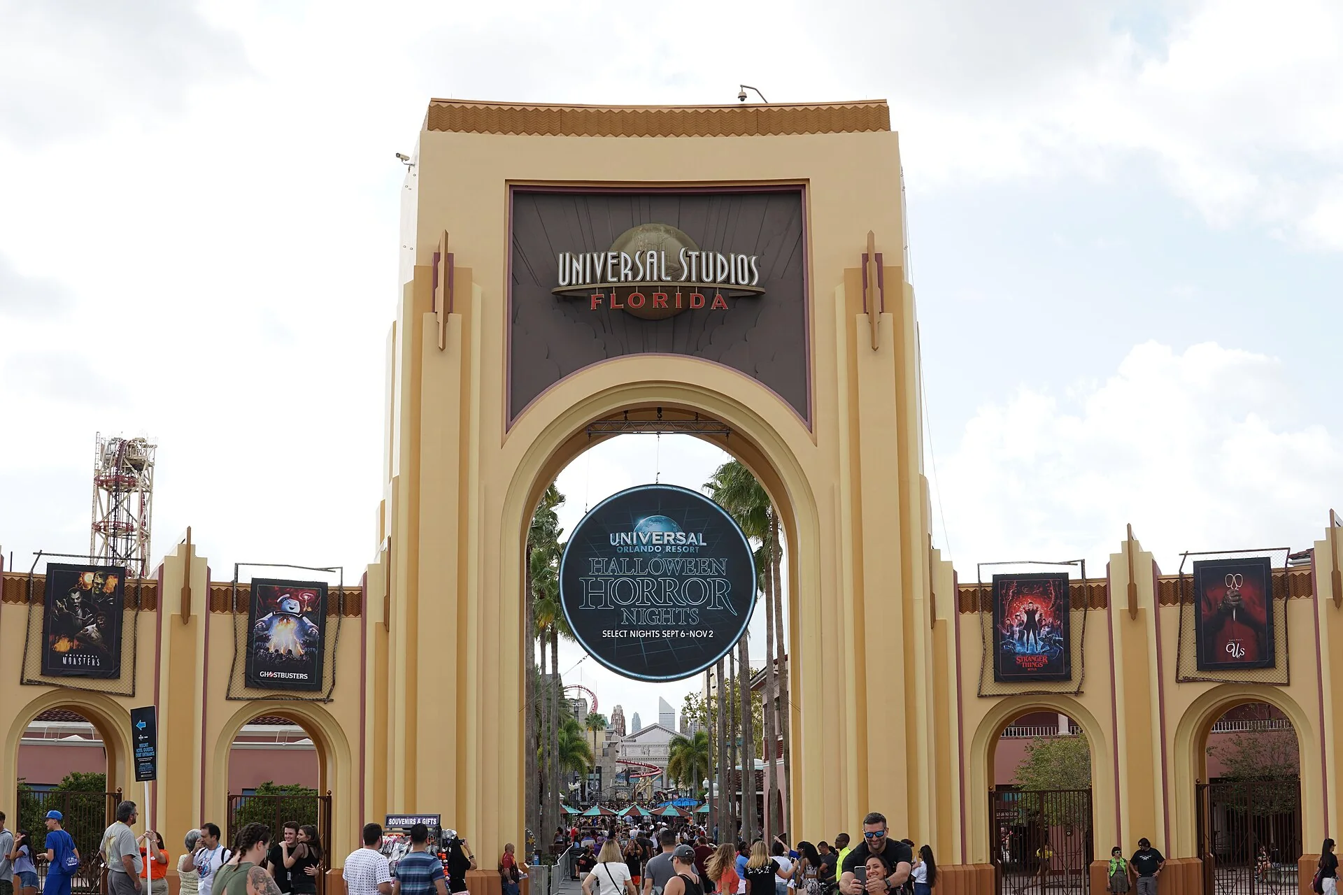 Arco de entrada do Universal Studios Florida com sinalização de Halloween Horror Nights 29 e visitantes durante o evento.