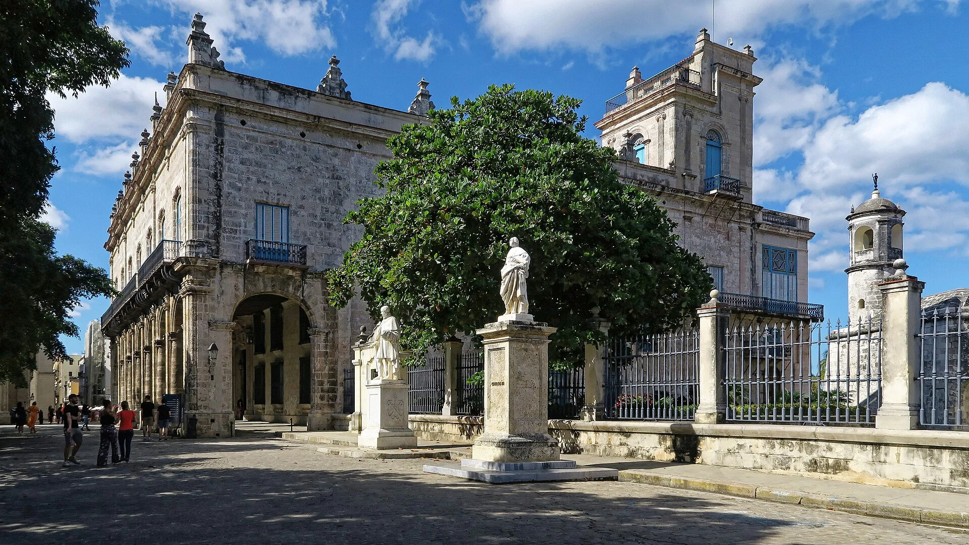 Arquitetura histórica, arcadas, esculturas e árvores no entorno do Castillo de la Real Fuerza, em Havana, sob luz natural.