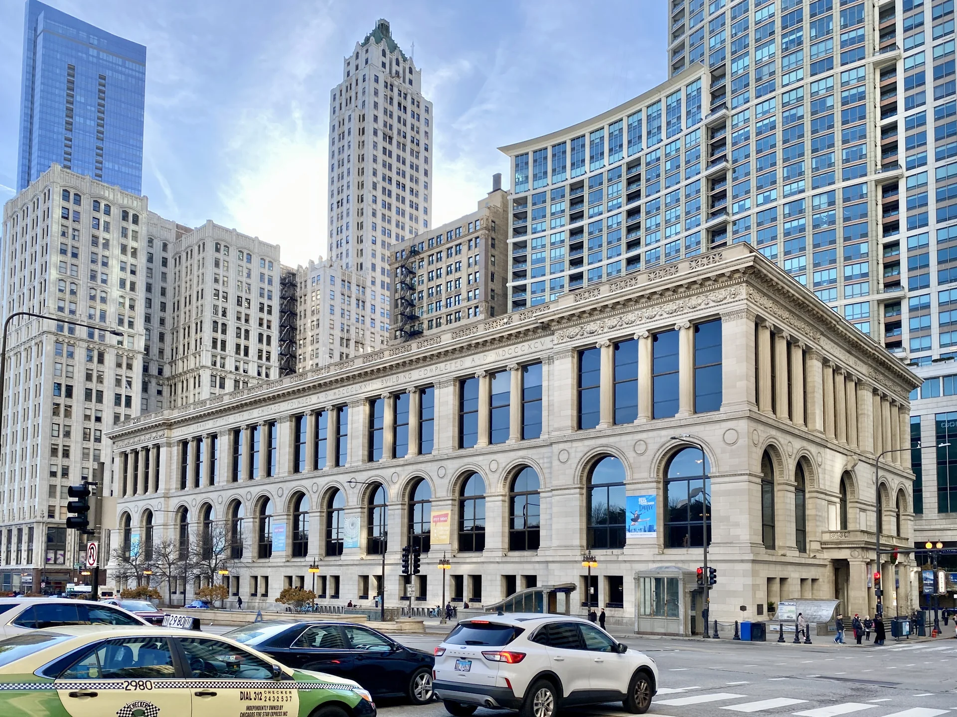 Fachada de pedra do Chicago Cultural Center vista da Michigan Avenue em dia claro, com edifícios do Loop ao fundo.
