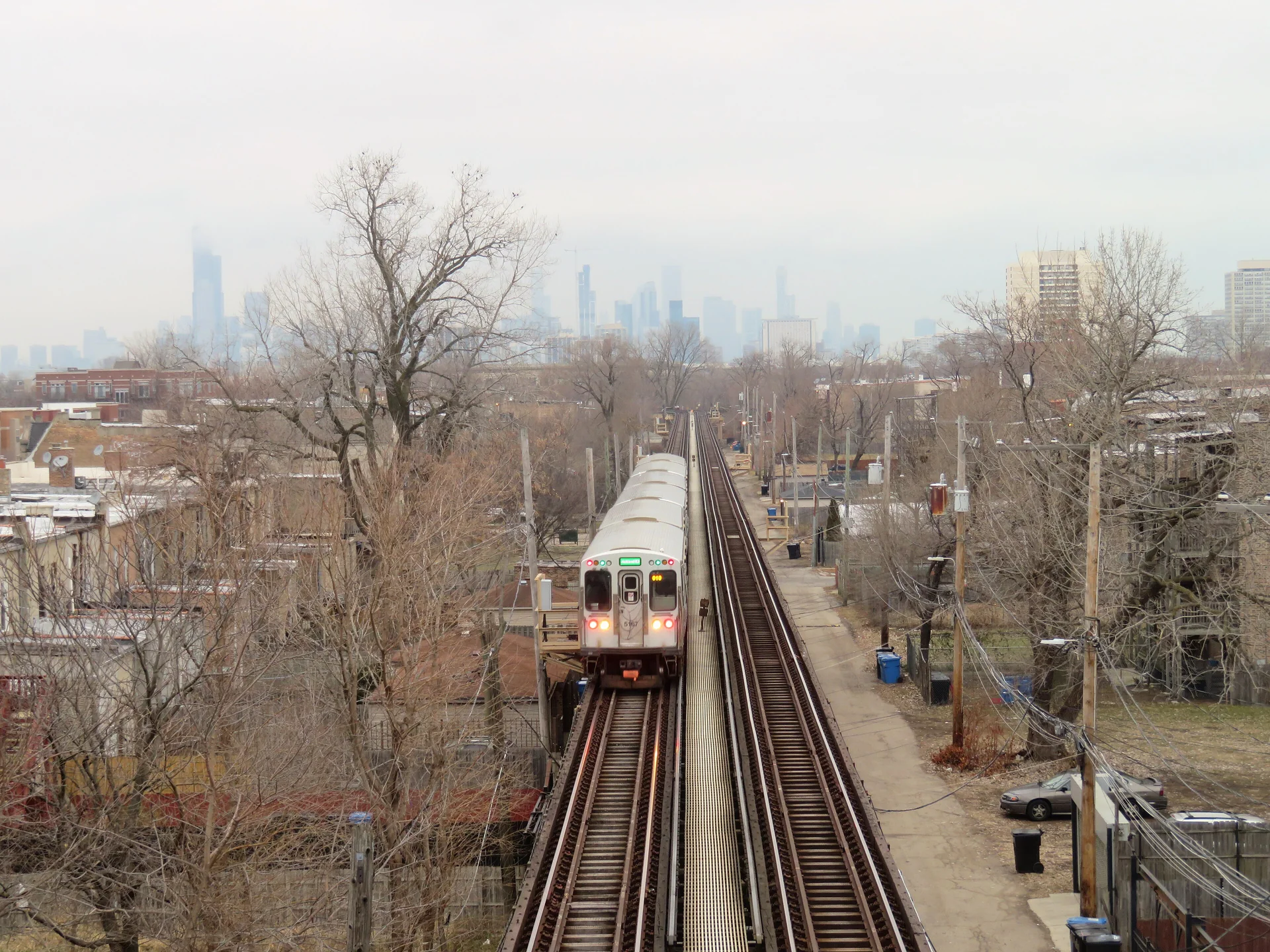Trem da CTA Green Line segue em via elevada perto da estação 43rd, com o skyline de Chicago ao fundo em luz diurna.
