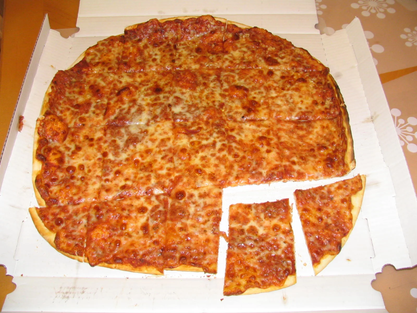 Pizza fina de Chicago cortada em quadrados, servida em uma caixa aberta.