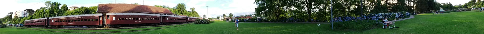 Panorama externo da Estação Ferroviária de Garibaldi, com composição de trem e gramado.