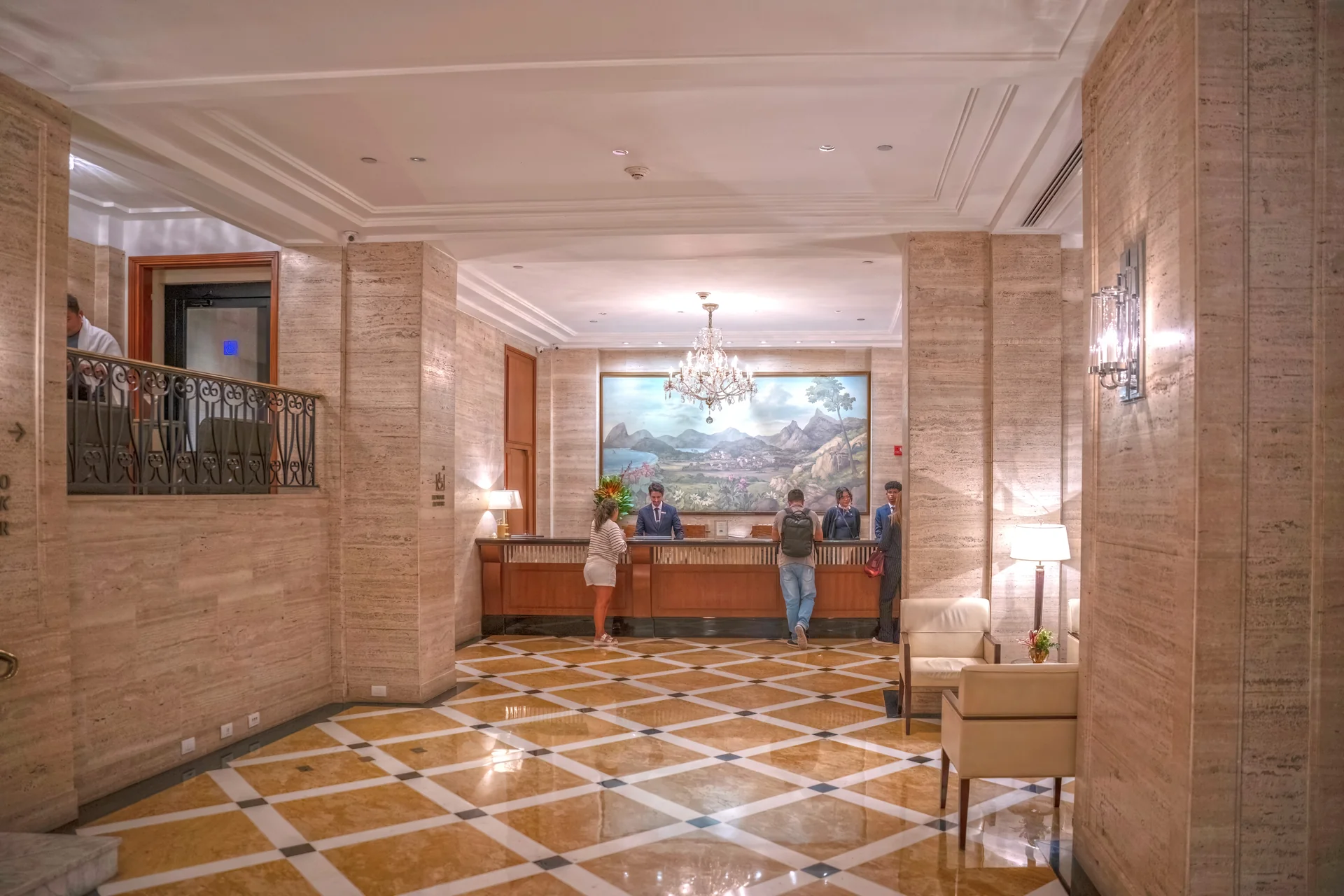 Recepção interna do Copacabana Palace com balcão de atendimento, piso geométrico e lustre.