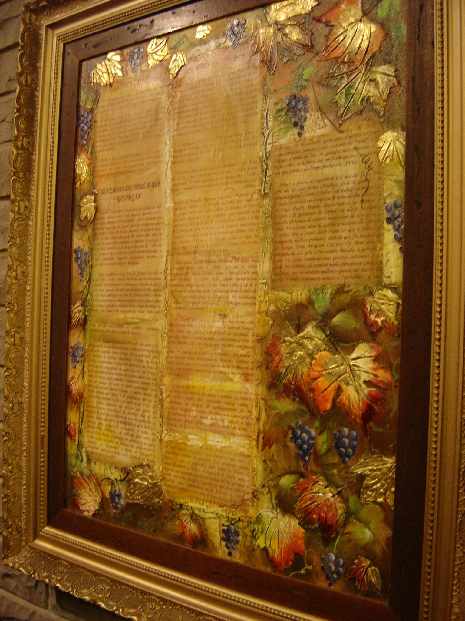 Fotografia de arquivo de 2008 de painel decorativo com texto e folhas de videira, identificada na coleção Casa Valduga do Wikimedia Commons.