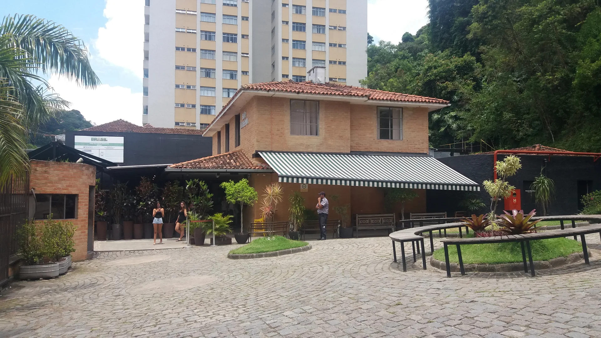 Área externa da Cervejaria Bohemia em Petrópolis, com mesas e edifícios ao redor.
