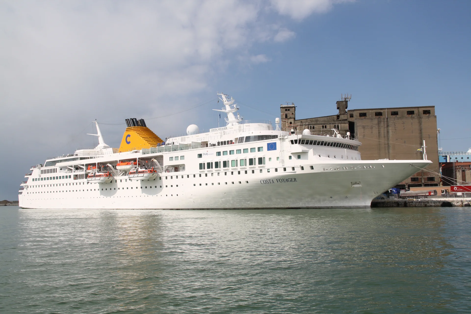 Fotografia histórica, de 2013, do navio Costa Voyager atracado no Porto de Livorno, sob luz diurna.