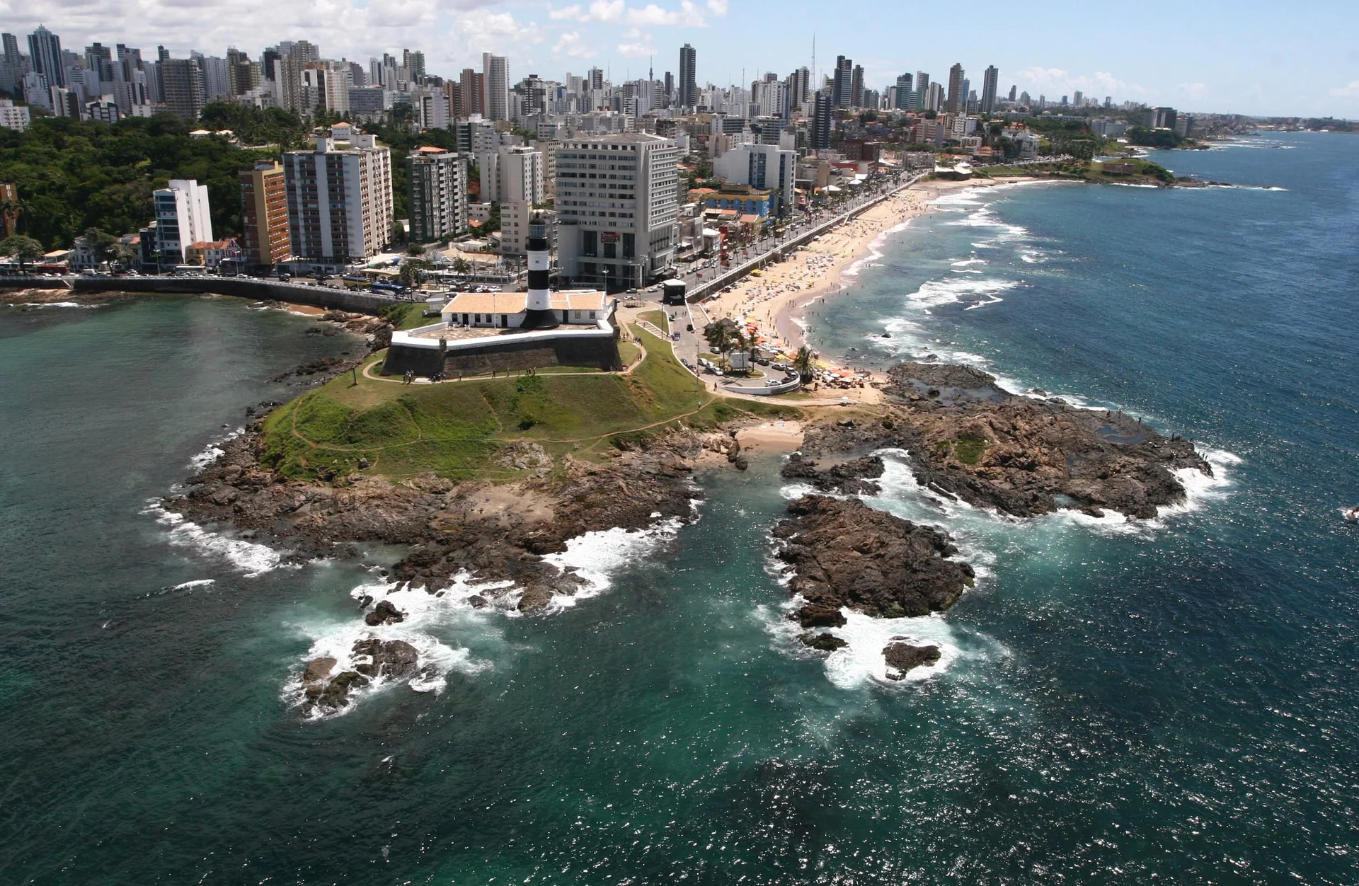 Imagem de contexto do destino: vista aérea clara do Farol da Barra e da orla de Salvador, Bahia; não representa o parceiro Flot Viagens, propriedade ou serviço.