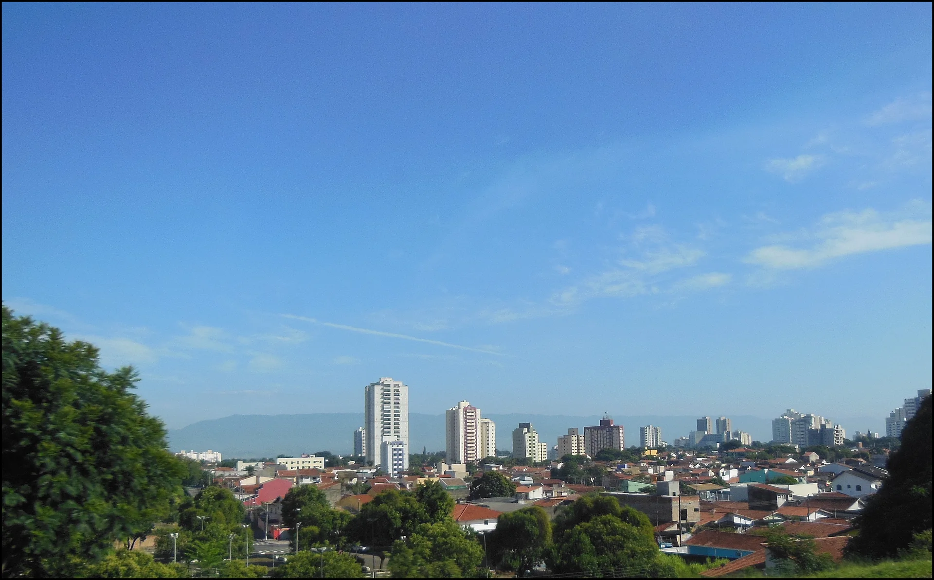 Contexto do destino: panorama diurno da paisagem urbana de Taubaté, com céu azul e serras ao fundo; esta imagem não representa o Hotel Fazenda Mazzaropi.