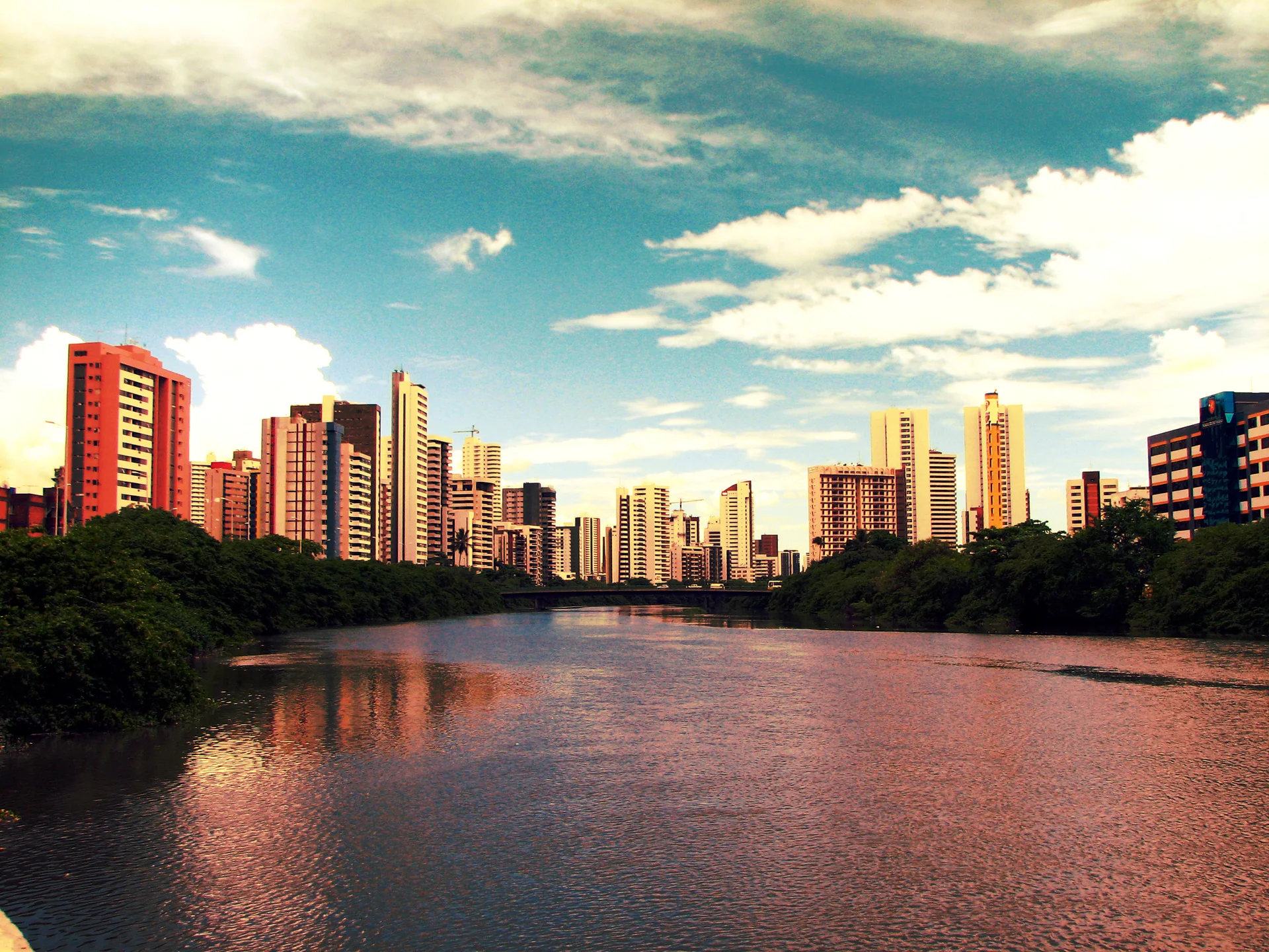 Imagem contextual do Rio Capibaribe e da paisagem urbana de Recife sob céu claro; não representa o parceiro Luck Receptivo, a propriedade ou o serviço.