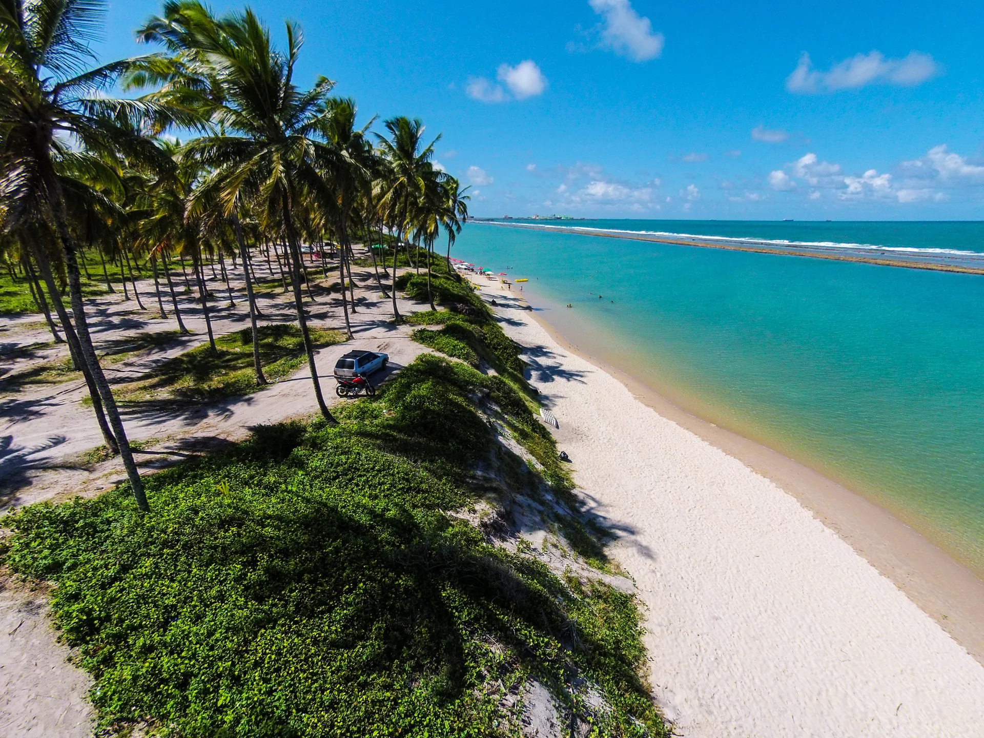 Faixa de areia, coqueiros e águas protegidas pelo recife em Muro Alto, Ipojuca; imagem do entorno, não do NANNAI Muro Alto.