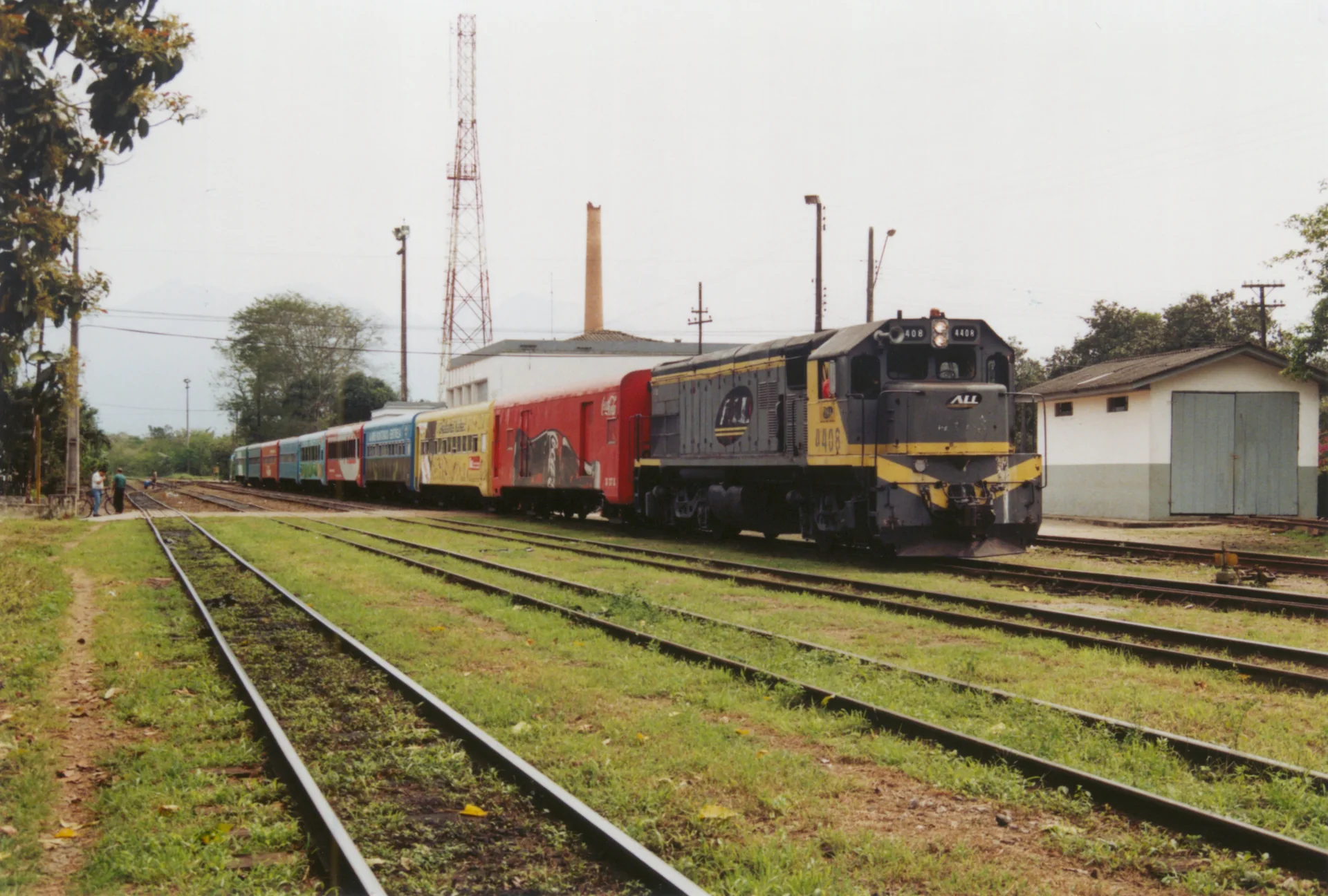 Trem Serra Verde Express em via férrea na estação de Morretes, sob luz diurna.