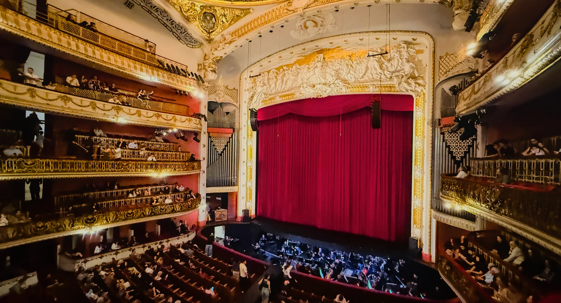 Auditório do Theatro Municipal de São Paulo com cortina vermelha, balcões ornamentados e plateias.